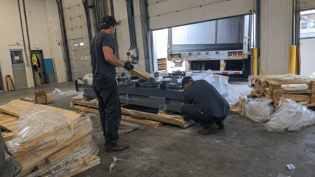 Industrial packaging workers performing crossdock recovery services by repacking and reblocking a shifted load at a commercial loading dock.